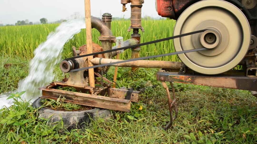 An old farm pump spraying water high into the air
